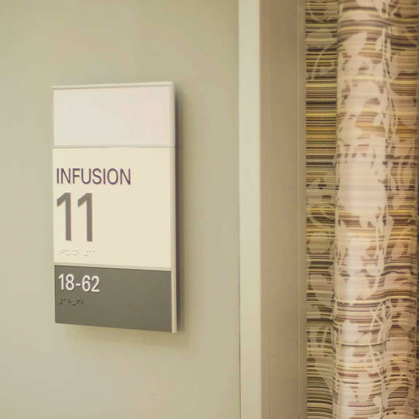 Hospital signage stating Infusion Room 11 with curtains closed next to it.