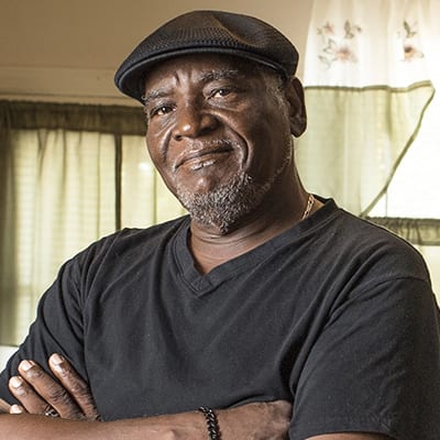 African American man with his arms crossed standing in his kitchen.