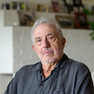 Elderly Caucasian American man sitting in his living room while wearing a black button up shirt.