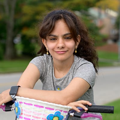 Young mixed race female child resting on her bicycle outside.